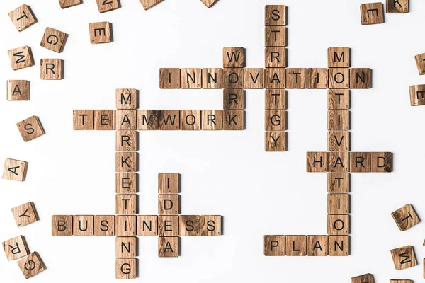 Business related words crossword spelled from wooden scrabble tiles lying on white table. Concept of building strong business team and success. 3d rendering