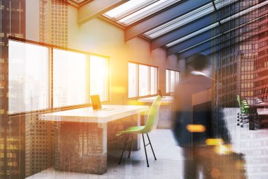 Köşesindeki gri duvarlar, kiremitli kat, satır, büyük taş ve ahşap masa dizüstü bilgisayarlar ve yeşil sandalye ile modern ofis iş adamı. Çift tonlu görüntü pozlaması bulanıklık