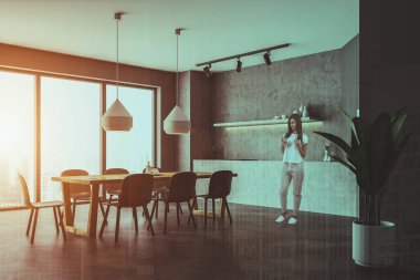 Kadın beton duvarlar, modern mutfak köşesinde döşeli kat, yapılı içinde fırın ve beton mutfak tezgahı ile gri dolap. Ahşap masa sandalye ile. Çift tonlu görüntü pozlaması