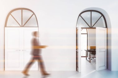 İç ofis koridorunda beyaz duvarlar ve zemin ve iki büyük beyaz ev ile iş adamı. Onlardan biri müdür ofis için açıktır. Tonlu görüntü bulanık