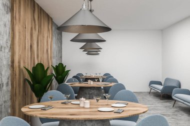 Beyaz, ahşap ve beton duvarlar, beton zemin ve onlara yakın duran mavi sandalye ile yuvarlak ahşap tabloları satırları ile modern café iç. 3D render