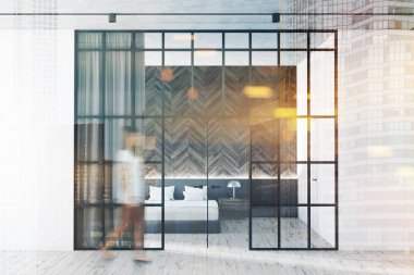 Ahşap ve gri duvarlar, ahşap zemin, beyaz karyola başucu masa ve rendeleyin kapı lobiye ile modern yatak odası iç kadında. Tonlu görüntü çift pozlama bulanık