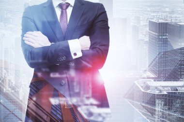 Tanınmayan işadamı cityscape arka plan üzerinde koyu takım elbise ve kırmızı kravat ayakta çapraz kollu giyiyor. Çift tonlu görüntü pozlaması