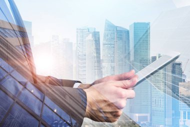 Tanınmayan işadamı ile tablet ayakta modern cityscape arka plan üzerinde yan görünüm. Çift tonlu görüntü pozlaması
