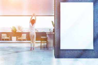 Gri duvarlar, modern mutfak kadında beyaz zemin, bej ve ahşap bar tabureleri ve koltuklar balkonda. Dikey poster duvara. Resim sahte tonda