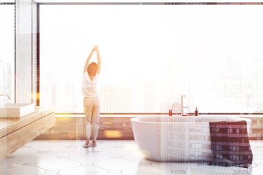 Beton duvarlar, modern banyo iç kadında döşeli kat, cityscape, beyaz küvet ve ahşap sayaç üzerinde beyaz lavabo duran panoramik pencereli. Çift tonlu görüntü pozlaması