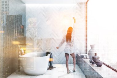 Modern banyo beyaz ahşap ve beton duvarlar ile iç kadında döşeli kat, cityscape ve beyaz küvet ile panoramik pencere. Çift tonlu görüntü pozlaması