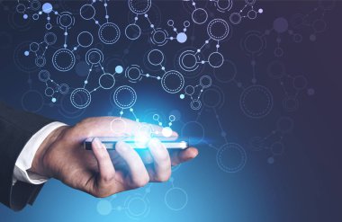 Tanınmayan işadamı smartphone--dan o koyu mavi arka plan üzerinde ortaya çıkan soyut daire arayüzü ile tutarak el. Çift tonlu görüntü pozlaması