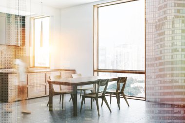 Kadın beyaz ve tuğla duvarlar, modern mutfak köşesinde döşeli zemin, gri ve ahşap mutfak tezgahı ve gri ve ahşap bar tabureleri ile. Ahşap masa sandalye ile. Çift tonlu görüntü pozlaması bulanıklık