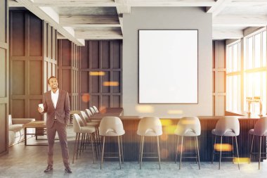 Afrika kökenli Amerikalı adam gri duvarlar, beton zemin, büyük pencereler, koyu ahşap ve gri bar gri sandalyeleri duruyor, gri kanepeler ile kaplı modern barda. Dikey poster. Resim sahte tonda