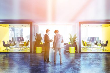 İki açık alan ofis sarı ve ahşap duvarlar, beton zemin, panoramik pencerelere, uzun ahşap mobilyalı kasalar ve aralarında lobide duran kanepeler ile. İşadamları konuş. Tonlu görüntü