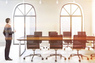 Toplantı salonu ile beyaz duvarları, kiremitli kat, kemerli windows ve siyah sandalye ile uzun, siyah ahşap masa ofis iç iş adamı. Tonlu görüntü