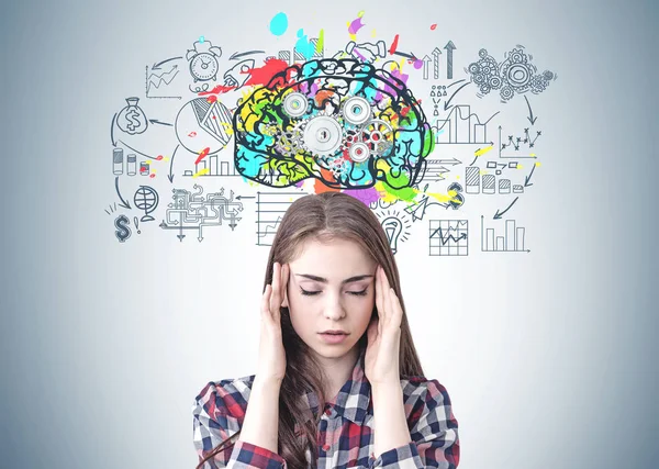 压力大的年轻女子穿着格子衬衫 头痛坐在灰色墙附近 大脑素描五颜六色 有齿轮和商业图标 — 图库照片