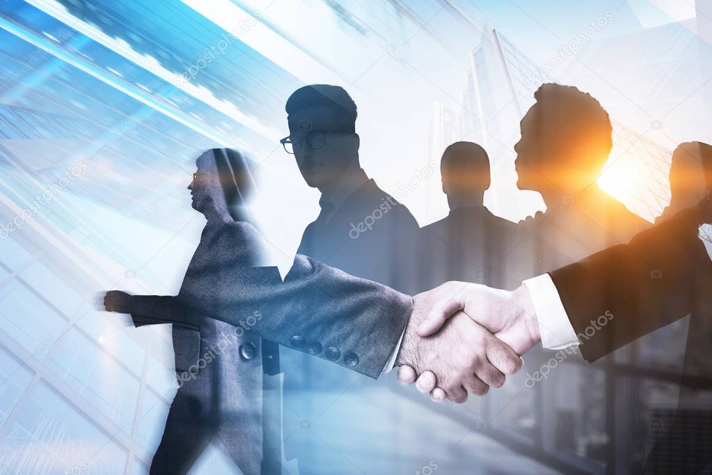Unrecognizable businessmen shaking hands in office with double exposure of business team and cityscape background. Toned image blurred