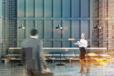 Erkek ve kadın iç Gri duvarlar, beton zemin, uzun gri kanepe yuvarlak siyah masa ve ahşap sandalyeleri ayakta ile modern Cafe. Tonlu görüntü çift pozlama bulanık