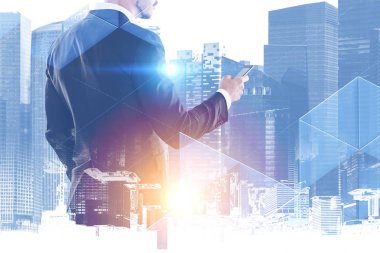 Tanınmayan sakallı iş adamı onun smartphone ekran ayakta, cityscape arka plan üzerinde seyir. Çift tonlu görüntü pozlaması