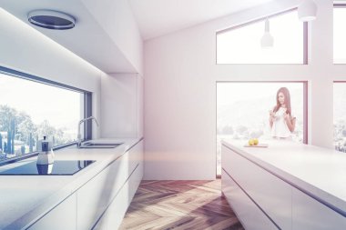 Beyaz duvarları, ahşap zemin, beyaz ada ve yapılı içinde lavabo ve Ocak ile beyaz mutfak tezgahı ile modern mutfak iç kadında. Tonlu görüntü