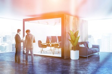 Beyaz ve ahşap ofis uzun ahşap bilgisayar masa ve sandalyeler beton zemin ve kanepeli panoramik office lobide duran iki sıra yan görünüm. İki iş adamları konuş. Tonlu görüntü