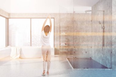 Beton duvarlar ve zemin, banyo iç kadında geniş pencere ve cam duvarlı duş küvet ayakta beyaz. Tonlu görüntü