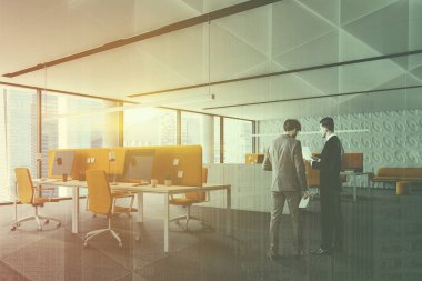 Modern ofis panoramik pencerelere, beyaz duvarlı köşesinde iki adam, beyaz ve sarı Bilgisayar masaları sarı sandalyeler ve sarı kanepeli duvara yakın. Çift tonlu görüntü pozlaması