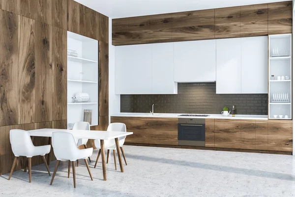 Corner of modern kitchen with black brick walls, concrete floor, wooden countertops and white cupboards and big white and wooden cupboard on the left. White table with chairs. 3d rendering