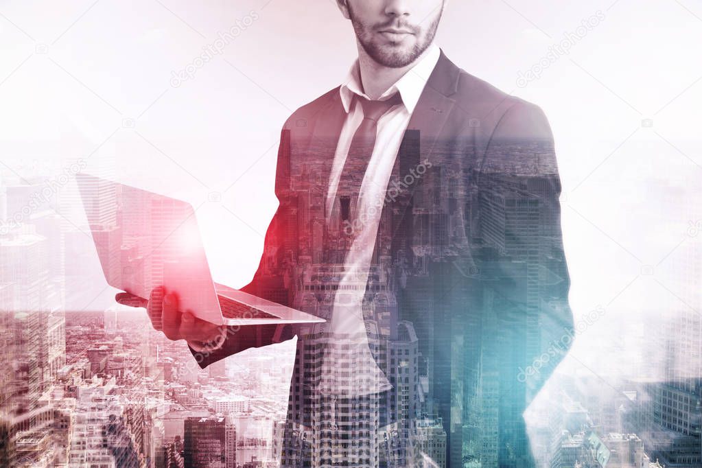 Unrecognizable bearded businessman in suit holding a laptop standing over modern cityscape background. Toned image double exposure