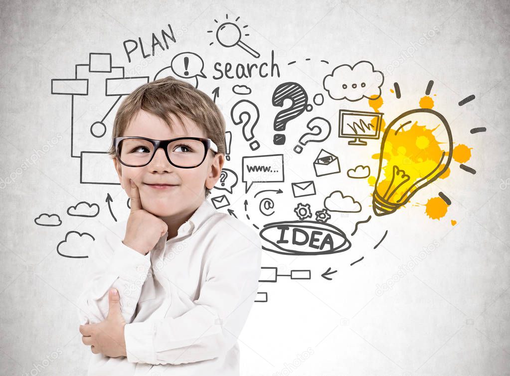 Adorable blond little boy wearing glasses and thinking standing near concrete wall with business plan sketch.