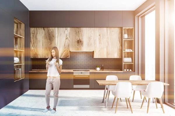妇女在现代厨房的内部 灰色的墙壁 水泥地板 灰色的台面和木制的橱柜和大灰色和木制的橱柜在左边 色调的图像 — 图库照片