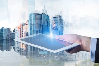 Tablet bilgisayar cityscape arka plan üzerinde ve onun yansıması tutan işadamı el. Çift tonlu görüntü pozlaması
