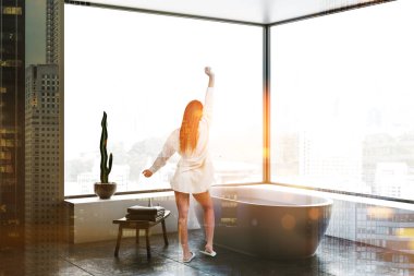 Kadın köşesindeki gri duvarlar, panoramik banyo kat, beyaz küvet ayakta ahşap sandalye ve beyaz çekmeceli döşenir. Çift tonlu görüntü pozlaması