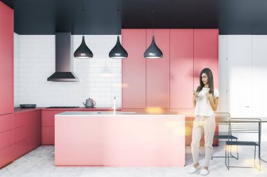 Kadın iç beyaz tuğla duvar, beton zemin, pembe dolapları ve mutfak tezgahı ile modern mutfak, lavabo ile pembe ve gri ada ve siyah masa sandalye ile. Tonlu görüntü