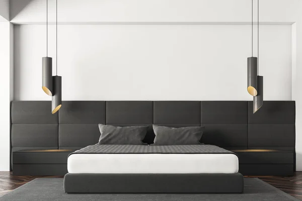 Interior of minimalistic bedroom with white walls, dark wooden floor, gray master bed standing on gray carpet, black bedside tables and stylish lamps. 3d rendering