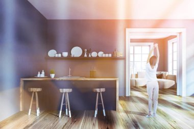 Gri duvarlar, ahşap zemin, ahşap tabureler olan gri ve ahşap çubuk, tabak ve oturma odası için kapı ile bir raf ile şık mutfak iç kadında. Tonlu görüntü