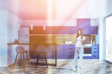 Kadın şık mutfak iç beyaz duvarlar, ahşap zemin, panoramik penceresi, mavi mutfak tezgahı ve dolapları ve mavi tabureleri olan çubuk. Tonlu görüntü