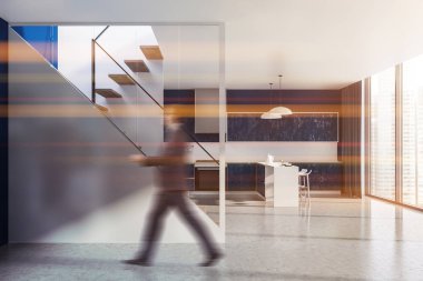 Mavi duvar, beton zemin, panoramik pencere ve onlara yakın beyaz ve mavi çubuklu ahşap mutfak tezgahı ile şık mutfak iç adam. Merdiven. Görüntü bulanık tonda