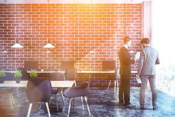 İşadamları iç loft Office tuğla duvarlar, siyah zemin, duvar ve daha küçük ahşap masa gri sandalye ile birlikte uzun ahşap bilgisayar tablo. Tonlu görüntü