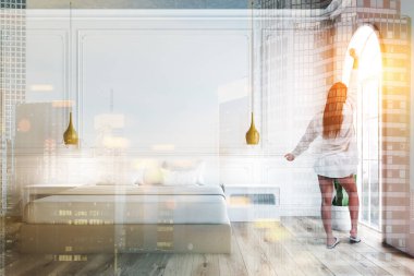 Yatak odası beyaz duvarlı iç kadında kemerli pencere eşiği, ahşap zemin ve bej ana yatak beyaz başucu masaları ile. Çift tonlu görüntü pozlaması