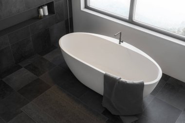 Modern banyo beyaz ve siyah taş duvarlar ve siyah seramik zemin gri havlu ayakta beyaz banyo küvetinde üstten görünüm. 3D render