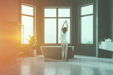 Gri duvarlar, beton zemin, beyaz, gri havlu küvet banyo iç kadında beyaz çift lavabo ve gri raflar. Çift tonlu görüntü pozlaması