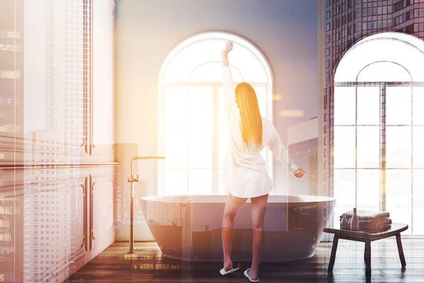 Pembe ve beyaz duvarlı, ahşap zemin, minimalist banyo iç kadında windows ve havlu ile ahşap sandalye beyaz banyo küvetinde sonraki için kemerli. Çift tonlu görüntü pozlaması