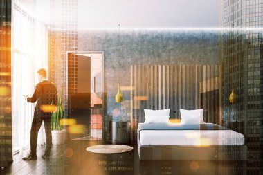 Beton duvarlar, koyu ahşap zemin, yuvarlak başucu masaları ve açık kapı tuvalete gri yatak yatak odası iç adam. Çift tonlu görüntü pozlaması