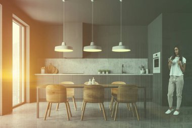 Modern mutfak Gri duvarlar, beton zemin, lavabo ve fırın ile gri mutfak tezgahı ve ahşap sandalye tabloyla iç kadında. Çift tonlu görüntü pozlaması