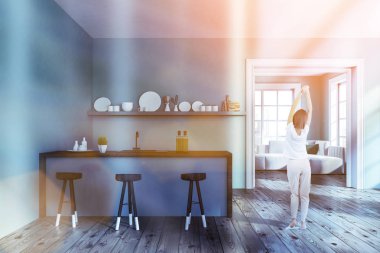 Mavi duvar, ahşap zemin, koyu ahşap tabureler olan mavi ve ahşap çubuk, tabak ve oturma odası için kapı ile bir raf ile şık mutfak iç kadında. Tonlu görüntü