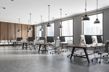 Açık alan ofis gri ve koyu ahşap duvarlar, çatı windows, beton zemin ve koyu ahşap bilgisayar tabloları satırları iç. 3D render