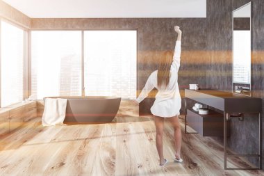 Gri duvarlar, ahşap zemin, bir havluda ve uzun tezgah üzerinde gri lavabo ile gri küvet ile panoramik banyo iç kadında. Tonlu görüntü