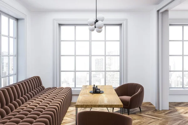 现代客厅的内部 白色墙壁 木地板 长长的棕色沙发和扶手椅站在木桌旁 — 图库照片