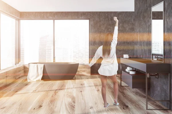 Gri duvarlar, ahşap zemin, bir havluda ve uzun tezgah üzerinde gri lavabo ile gri küvet ile panoramik banyo iç kadında. Tonlu görüntü