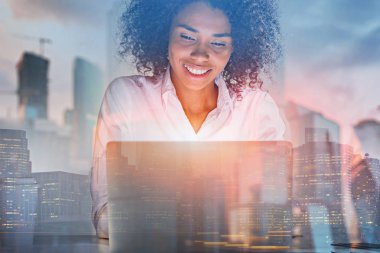 Afro-Amerikan işkadını dizüstü cityscape çift pozlama ile ofisinde çalışan gülümseyerek. Tonlu görüntü