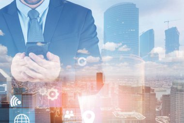 Tanınmayan işadamı iş arayüzü çift pozlama ile cityscape arka plan üzerinde duran akıllı telefon bakıyor. Tonlu görüntü