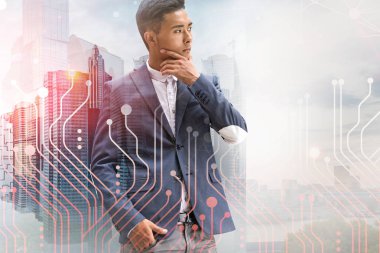 Devrelerin çift pozlama ile modern cityscape arka plan üzerinde duran düşünceli Asya işadamı portresi. Kavramı Merhaba teknik iş. Tonlu görüntü
